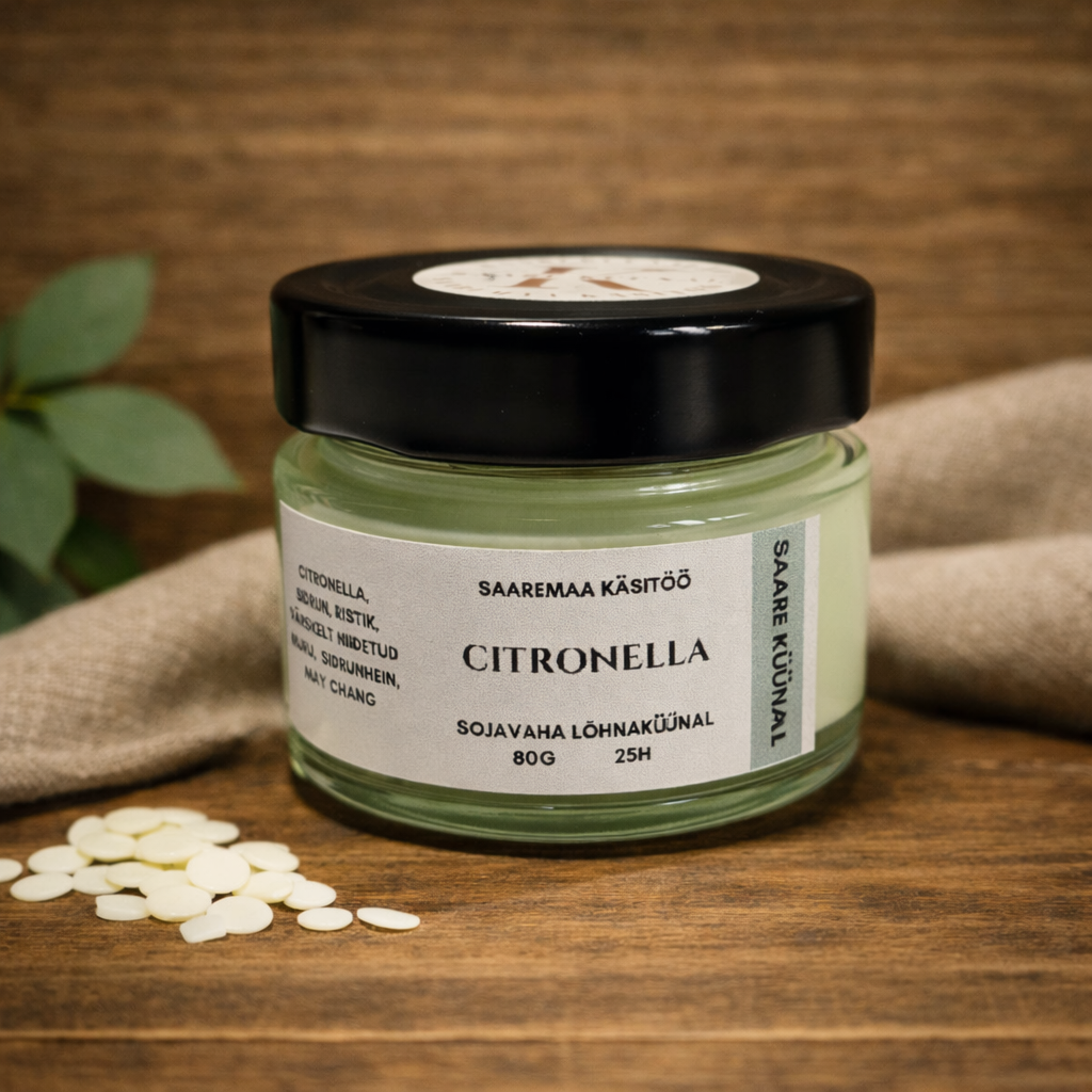 Citronella 80g käsitöö sojavahaküünal klaaspurgis, helel tammepuidust taustal, sinise lumehelbe kaunistusega ja ühtlase pehme valgusega.
