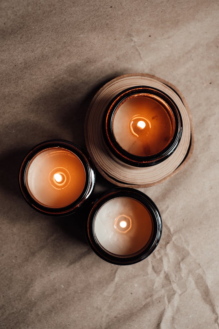 Top view of eco-friendly candles in glass jars on a rustic paper background, creating a warm minimalistic ambiance.